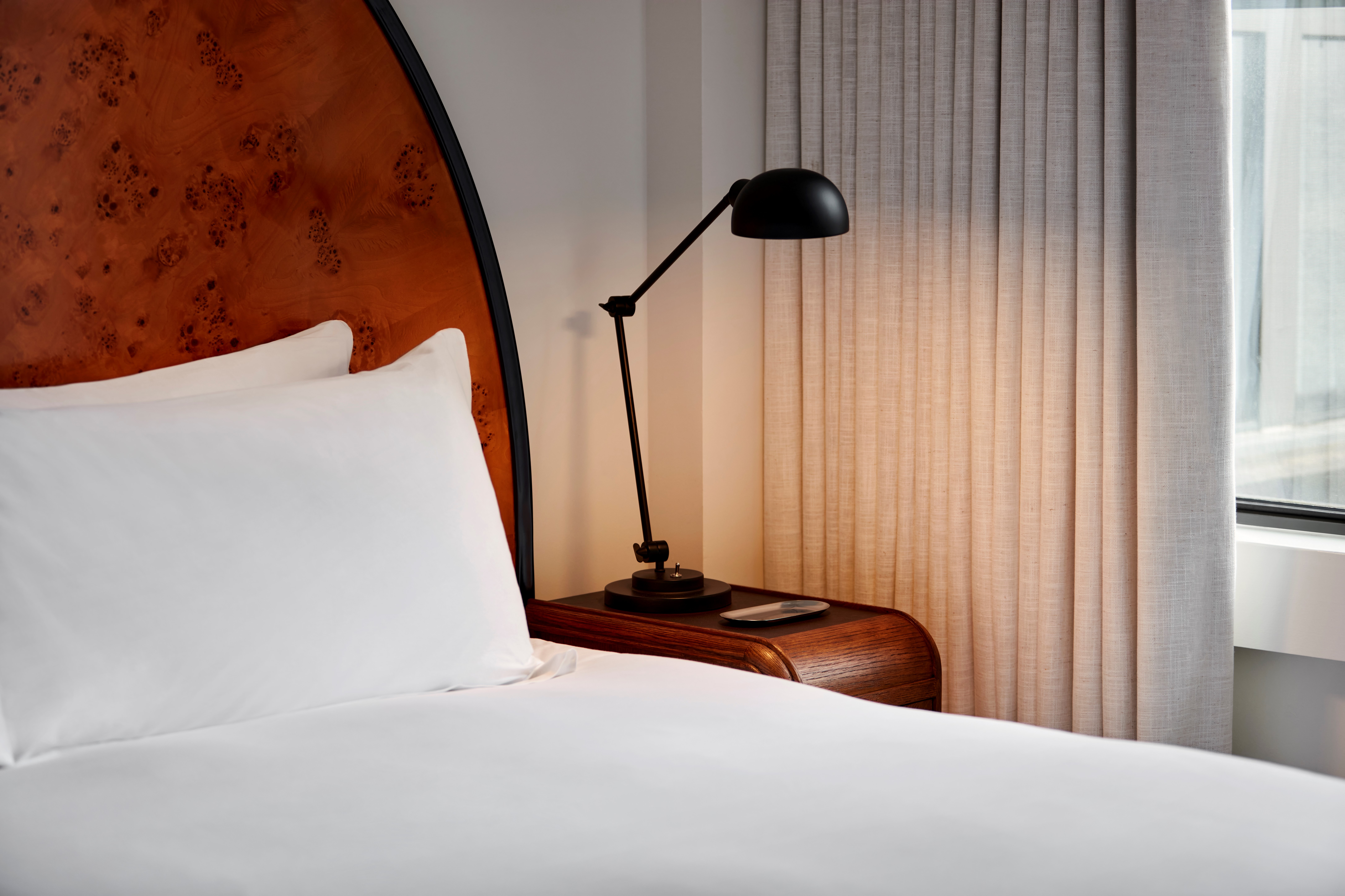 Detail of bed with bedside lamp at a Lyle hotel room.