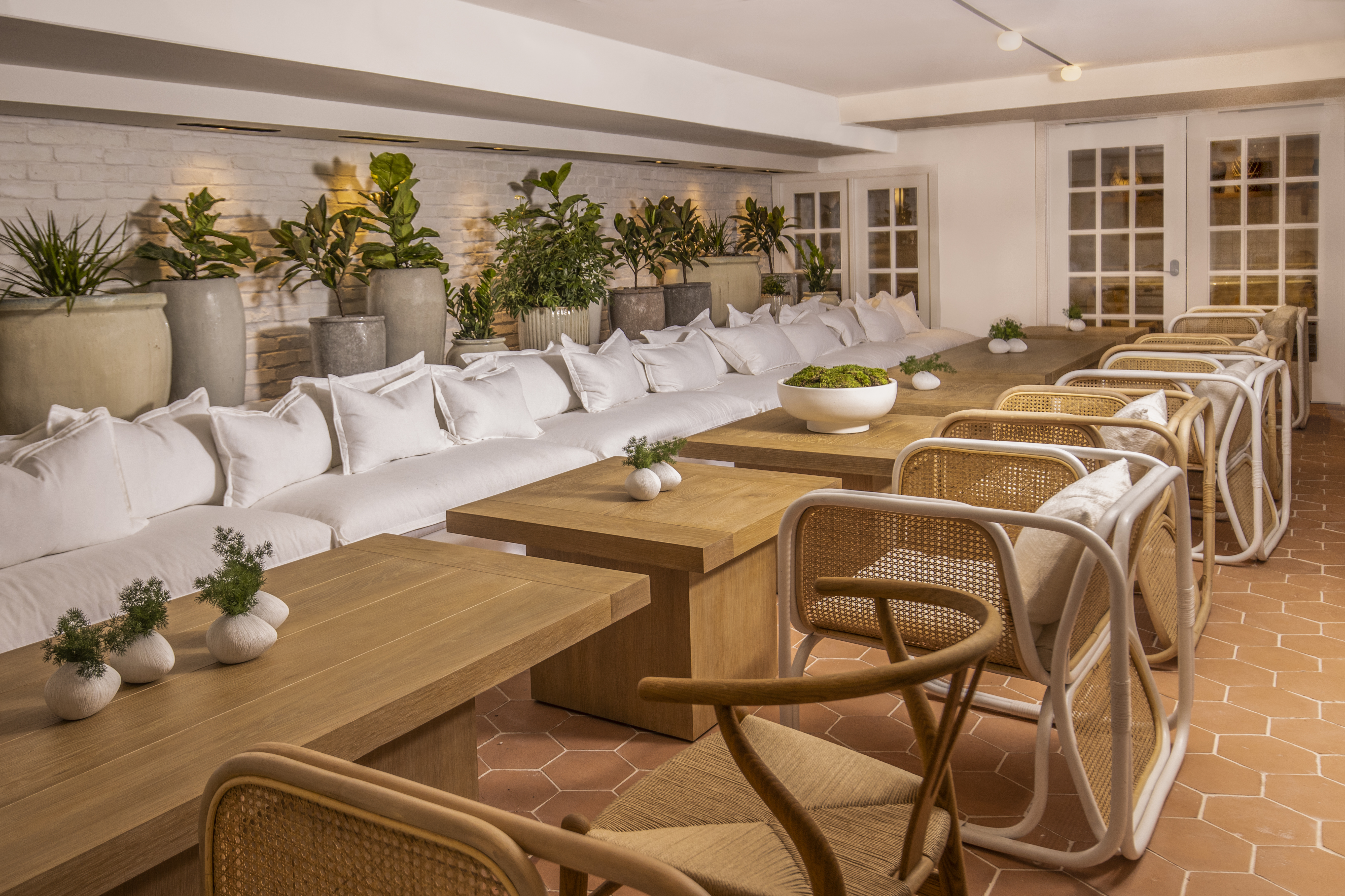 Long tables along white couches in the Conservatory at the Lyle DC.