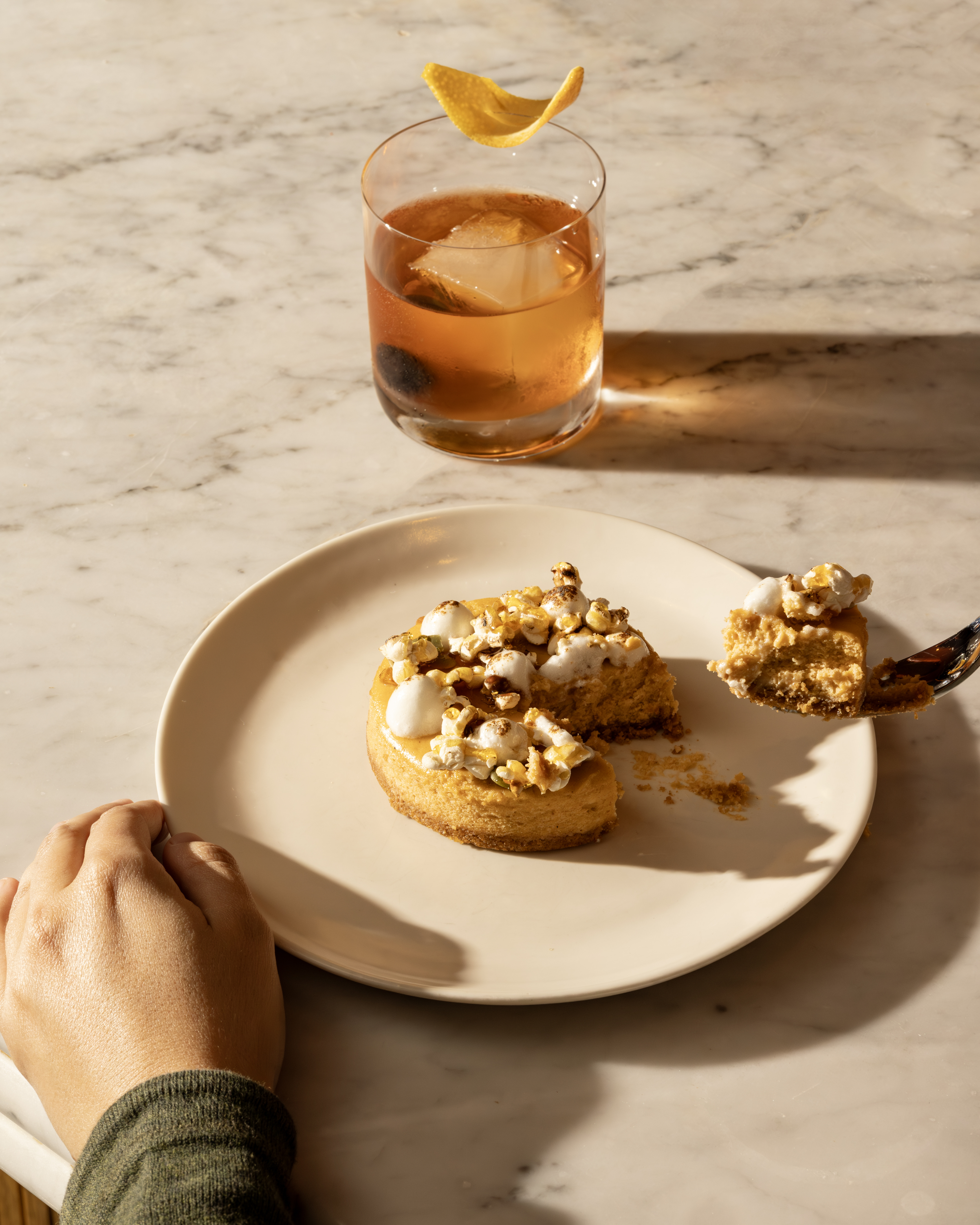 Autumnal dessert being lifted on fork with cocktail in background